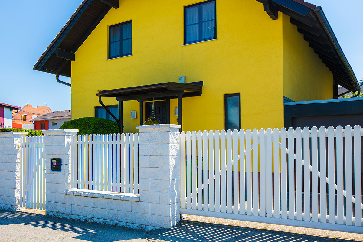 Schiebetuer und Gartentuer in Weiss aus Aluminium vor gelbem Haus