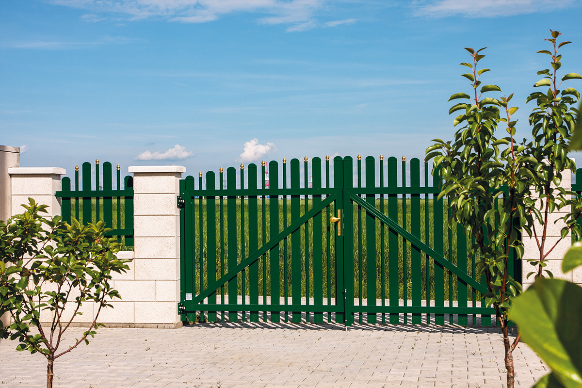 Klassisches Fluegeltor aus Aluminium in gruen mit gruenem Feld im Hintergrund