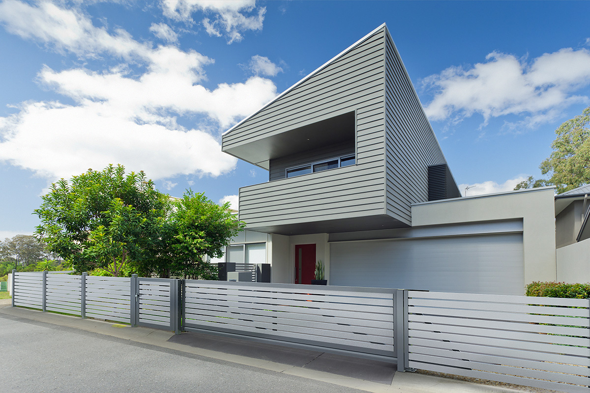 Querlattenzaun aus Aluminium in Silber mit elektrischem Fluegeltor und Gartentuer als Einfahrt mit Haus im gleichen Stil