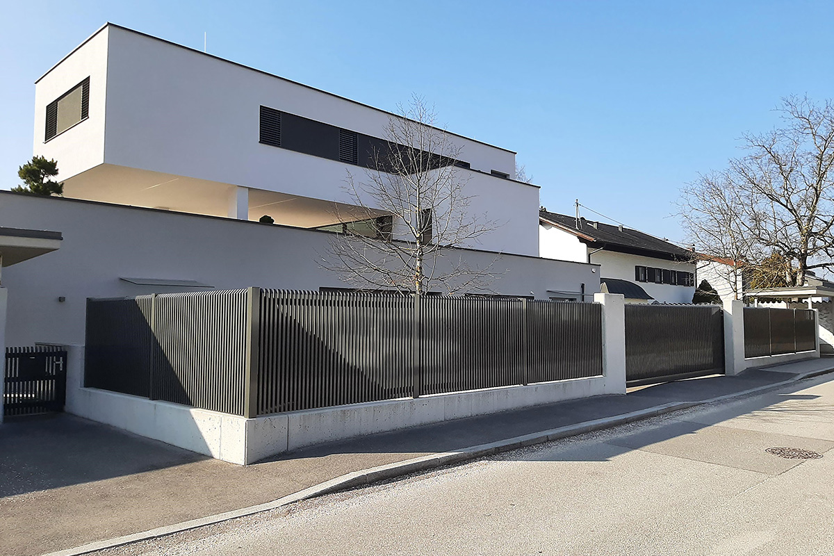 Stilvoller Zaun mit Schraegkappen aus Aluminium mit Sichtscutz vor modernem Haus