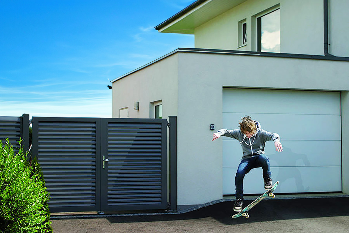 Blickdichte Alu Gartentuer neben Haus mit Kind auf Skateboard