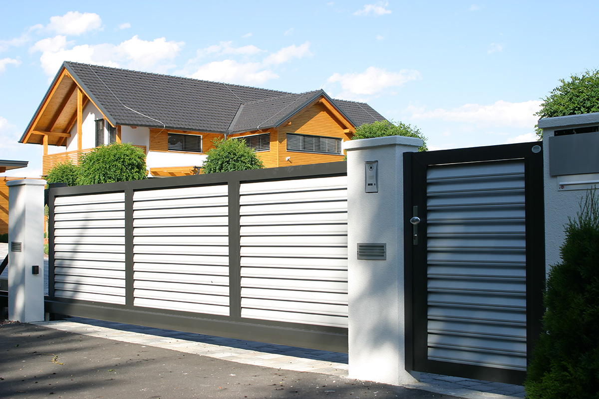 Blickdichte Schiebetuer elektrisch in schwarz weiss mit Gartentuer und Haus im Hintergrund