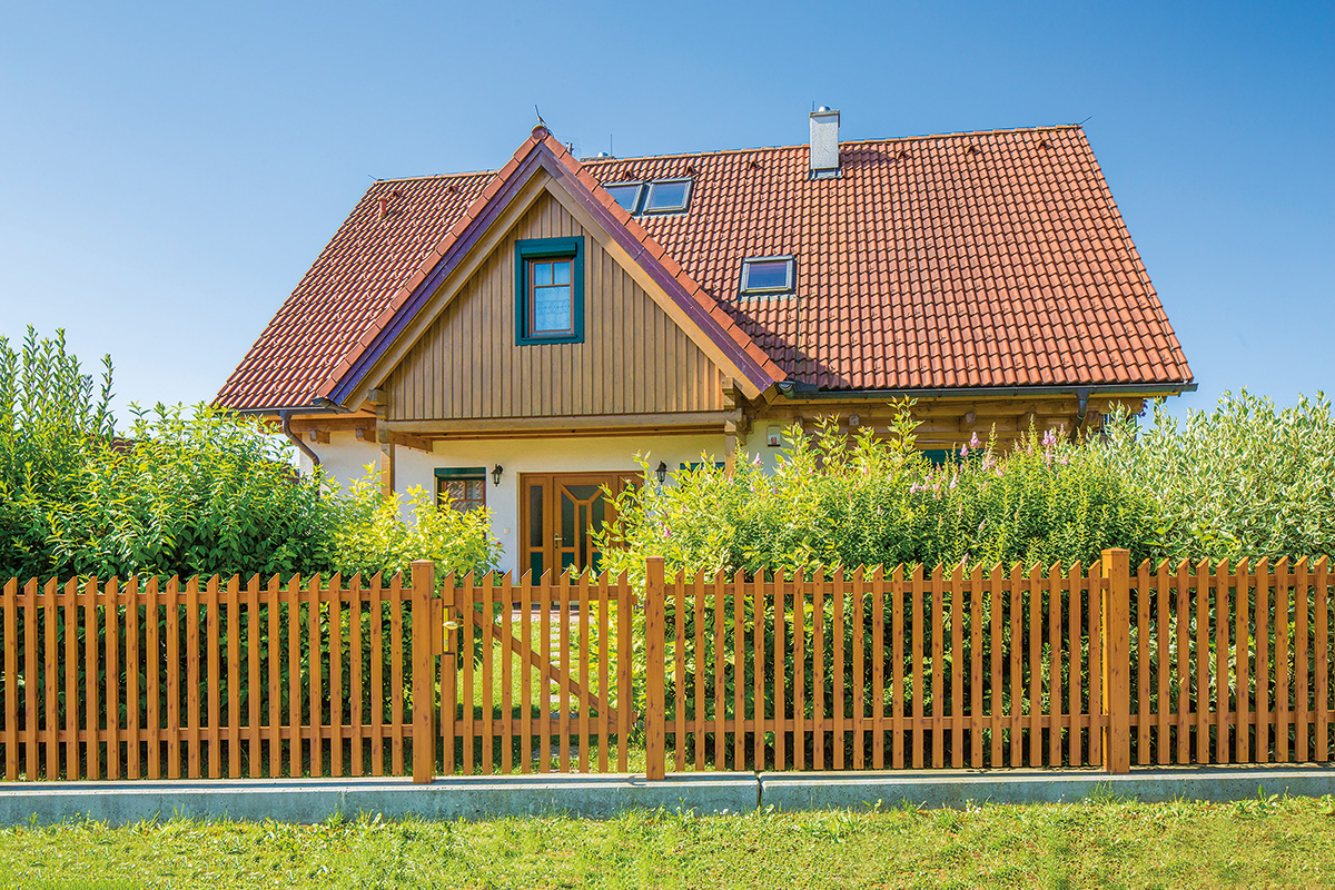 Zeitloser Gartenzaun aus Aluminium in Holz Optik als Einfahrt vor einem Haus aus Holz