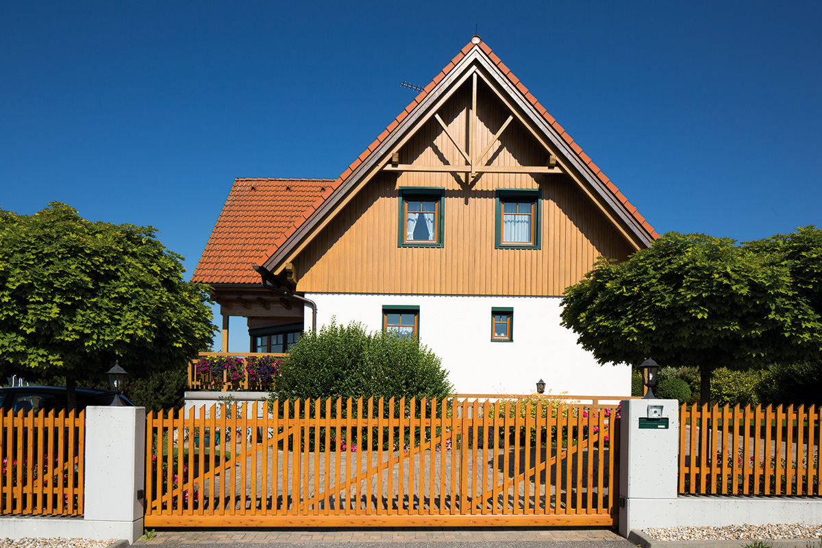 Klassische Schiebetuer aus Aluminium in Holzoptik vor traditionellem Haus