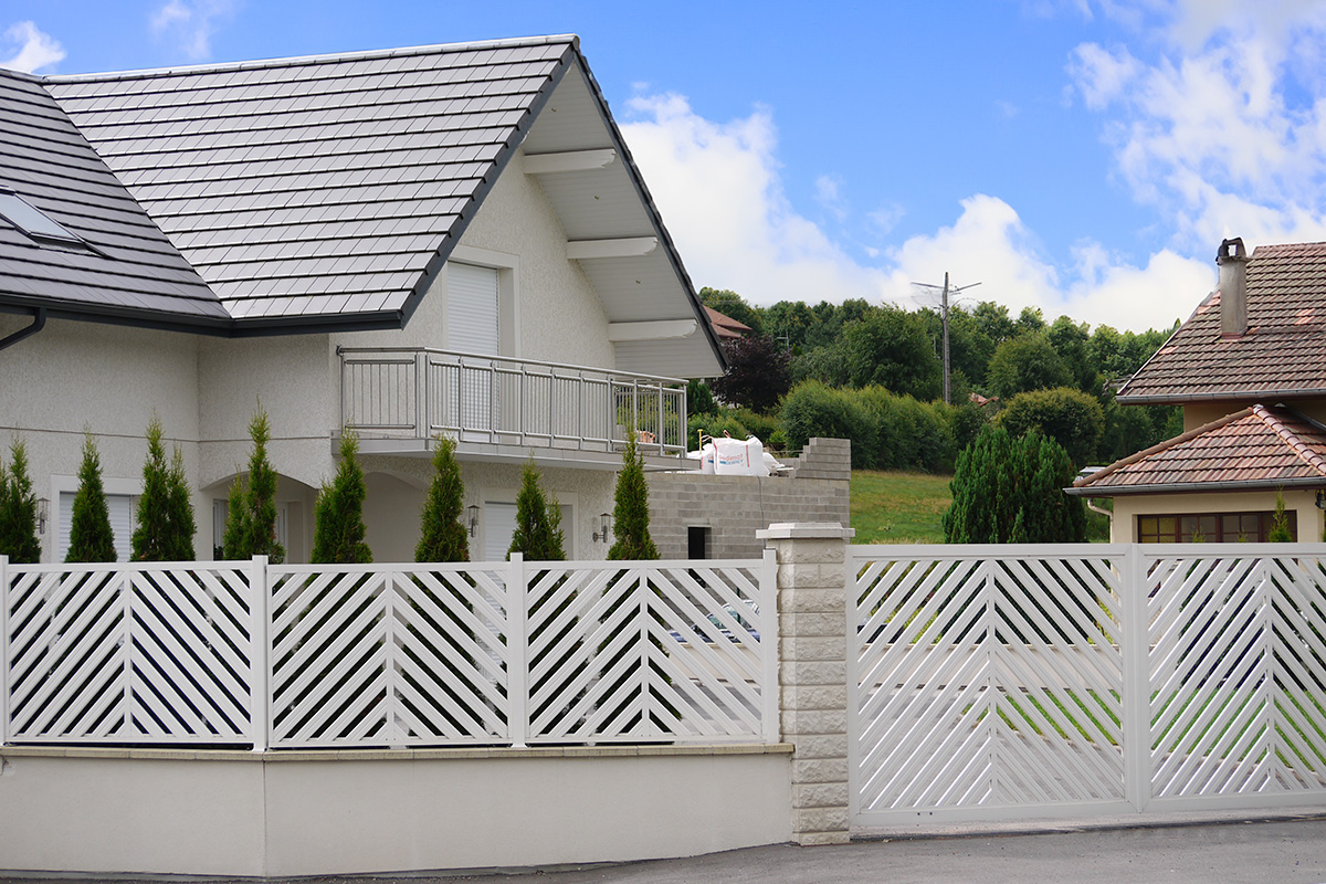 weisser Gartenzaun mit elektrischem Fluegeltor aus Aluminium als Einfahrt vor grossem Haus