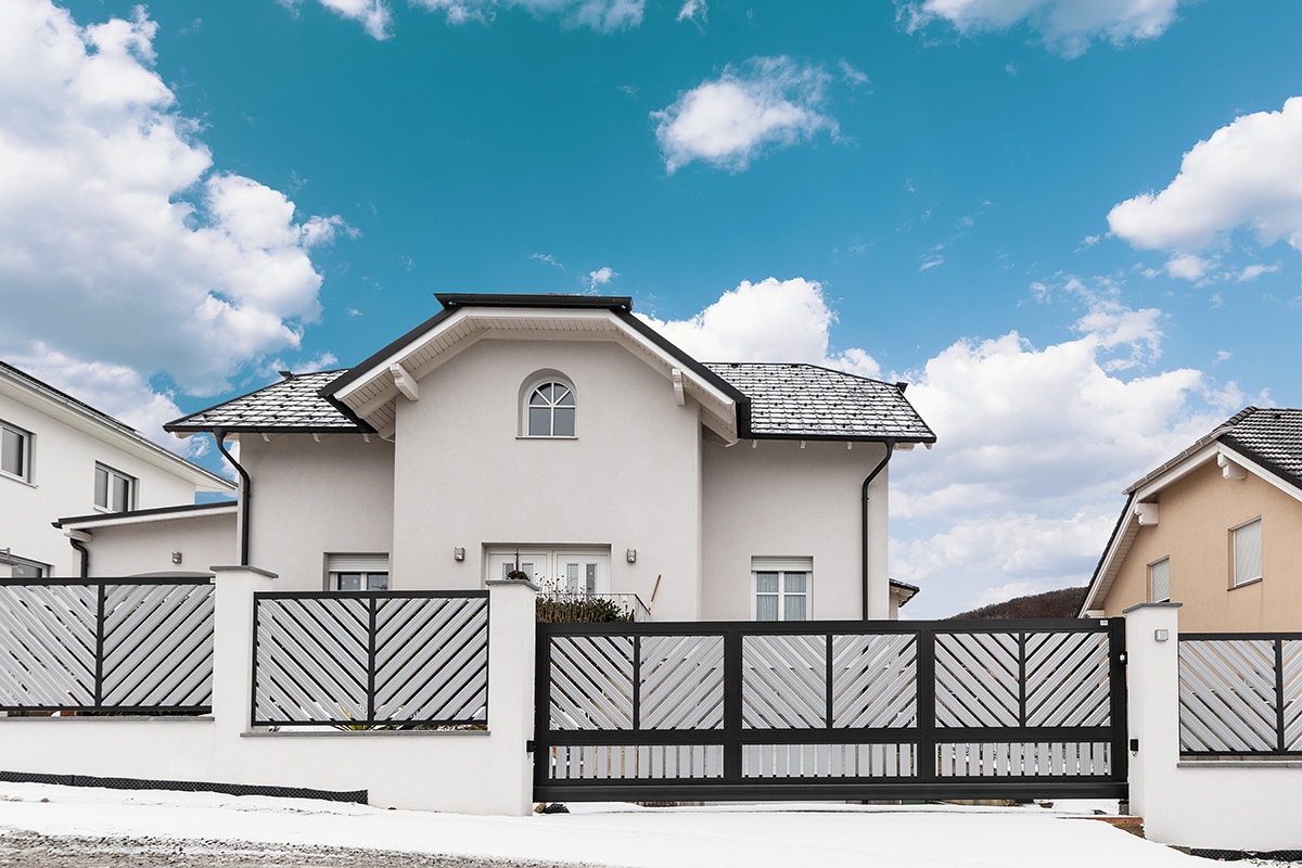Blickdichter Zaun mit elektrischer Schiebetuer in schwarz weiss vor grossem Haus