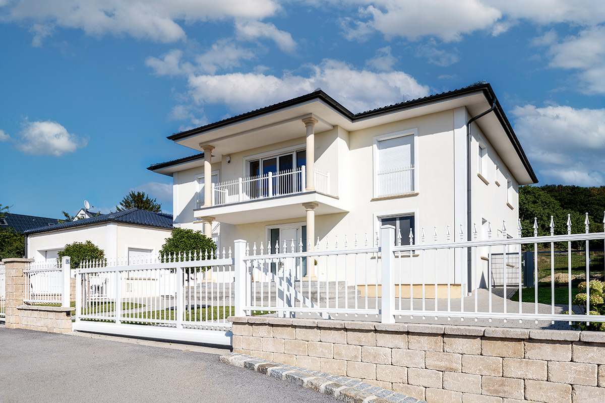 Klassische Schiebetuer elektrisch aus Aluminium in Weiss vor grosser Villa