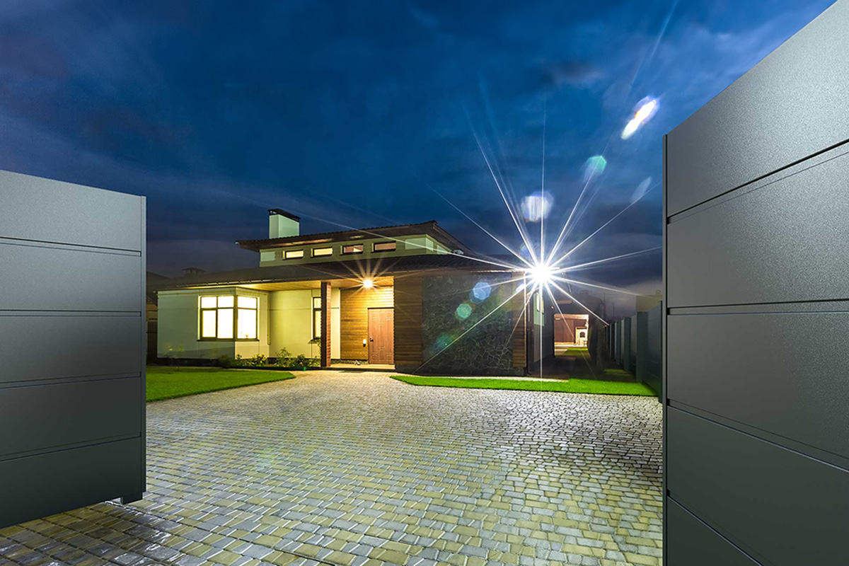 Modernes Fluegeltor in Anthrazit vor modernem Haus in der Nacht bietet perfekten Sichtschutz