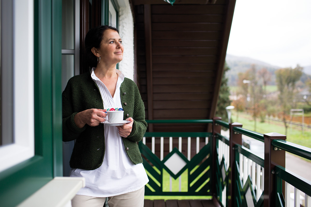 Auf dem Balkon mit einzigartigem Design geniesst eine Dame eine Tasse Kaffee