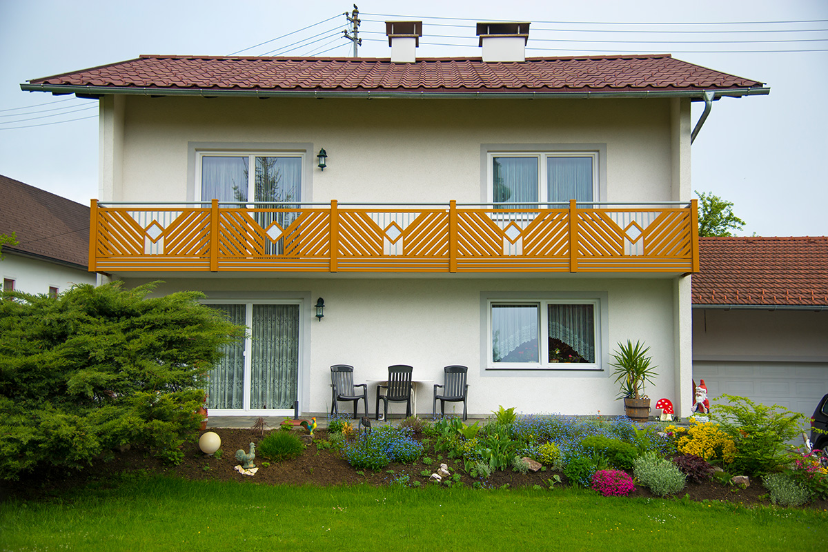 Balkongelaender aus Aluminium von GUARDI mit Holzoptik passend zum Einfamilienhaus mit Garten