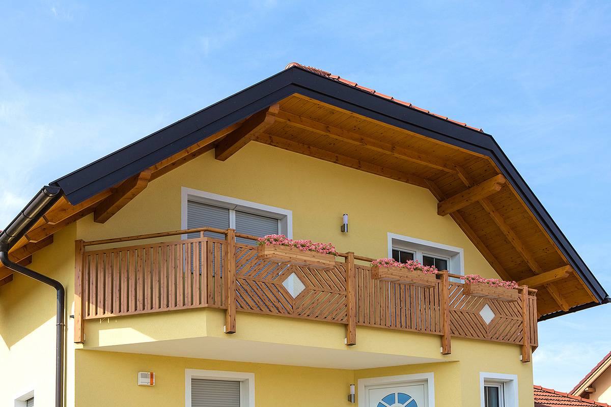 Balkon im Holzdesign an gelbem Haus