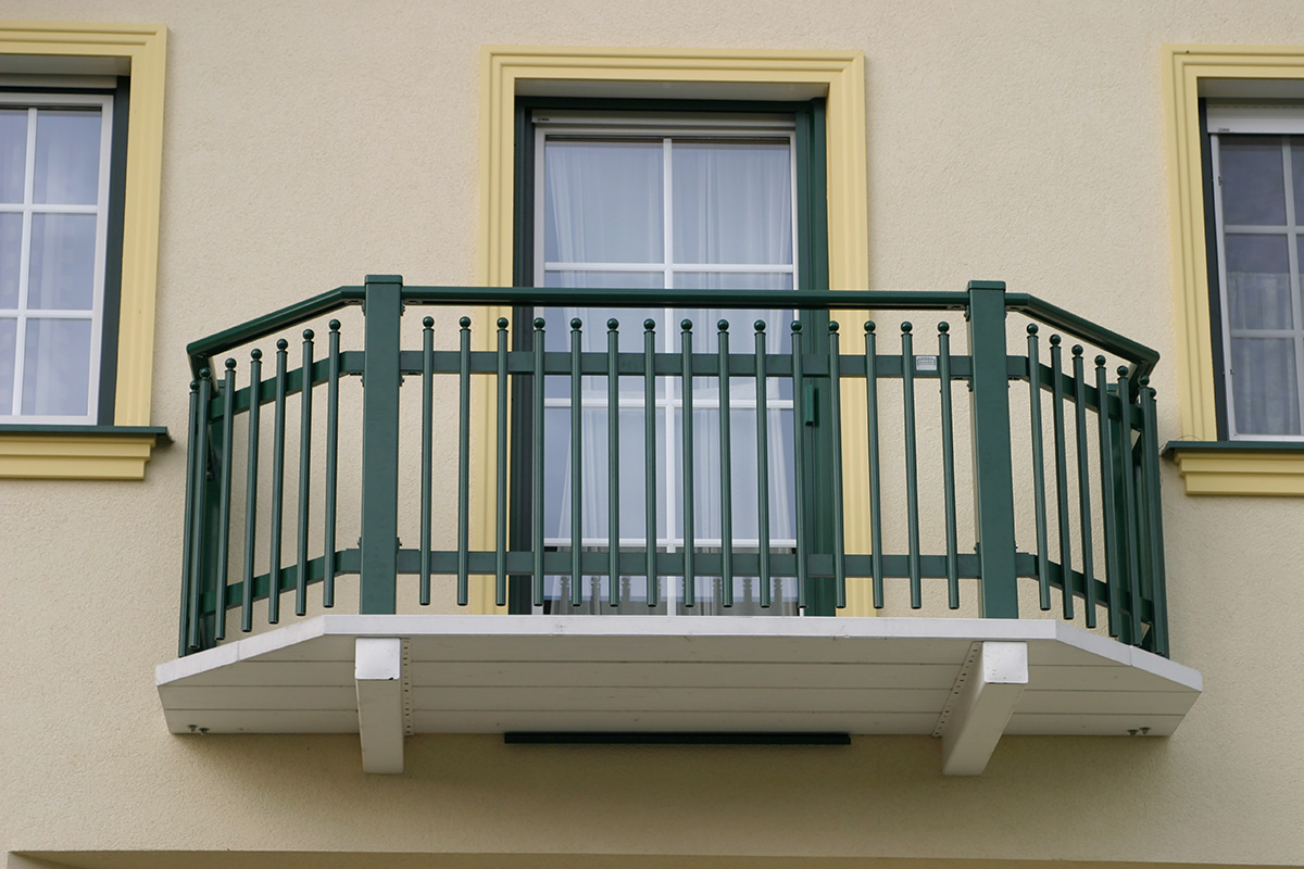 Balkon in grüner Farbe mit traditionellen Zaunspitzen