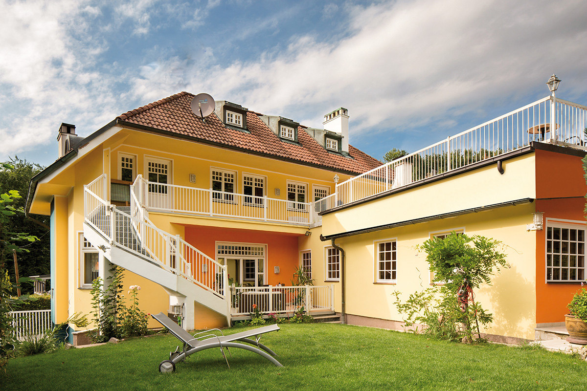 balkon rundstabmodel nach mass an grossem gelben haus mit garten