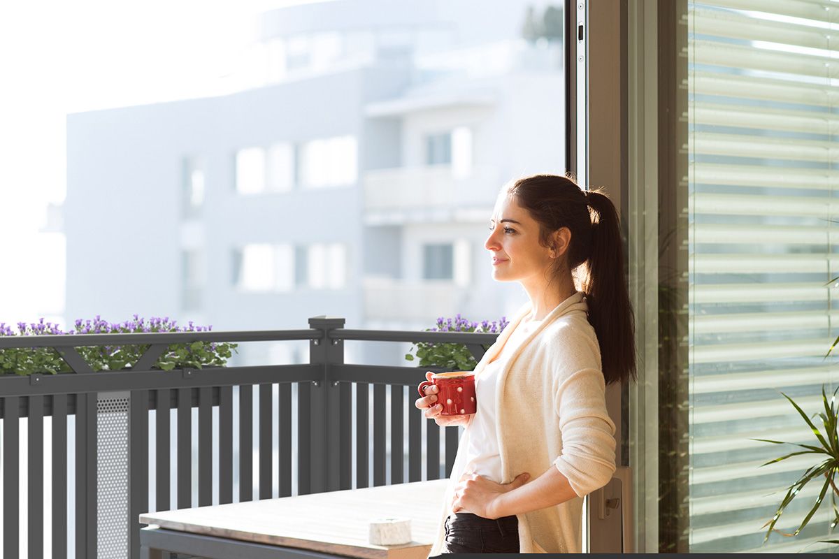 frau geniesst kaffee am balkon in neubauwohnungen