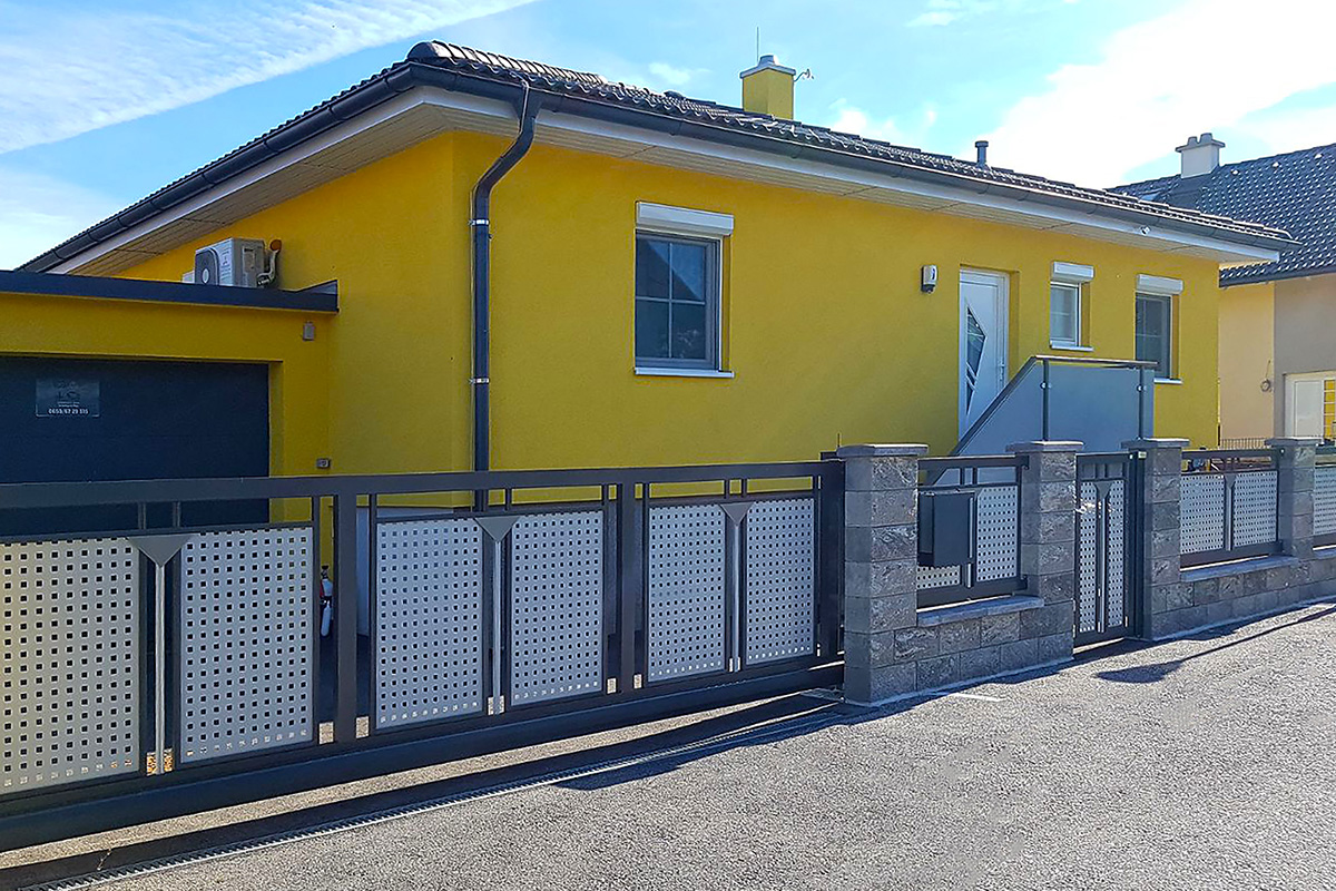 modernes schiebetor von guardi modell loskana vor gelbem einfamilienhaus