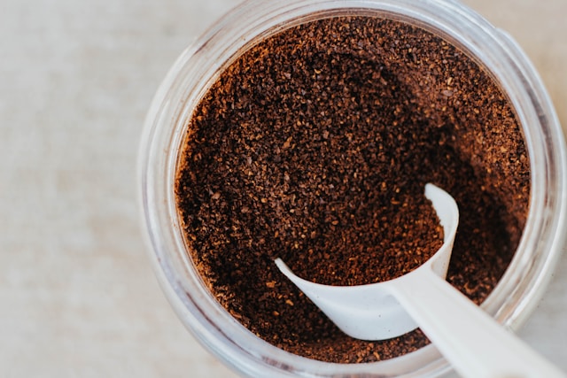 Kaffeesatz mit weißem Messloeffel im Glascontainer fuer Zero Waste Gardening