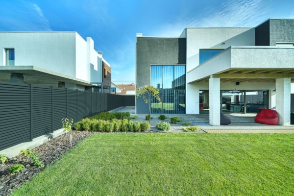 Großes Einfamilienhaus mit Garten, umzäunt von einem Sichtschutzzaun aus Aluminium mit Querlatten in anthrazit